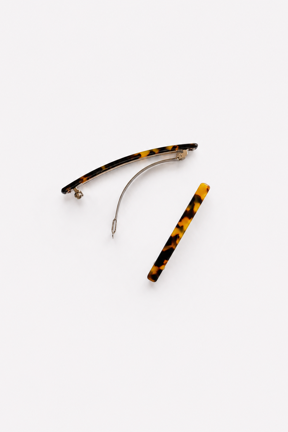 Two tortoiseshell hair claw clips on a light gray background, one displayed open and one closed, showing the amber, black, and yellow pattern with silver tone metal clasps - East Coast General