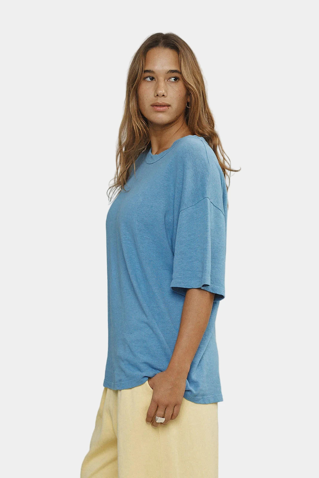 Woman wearing a blue t-shirt and yellow pants against a plain background