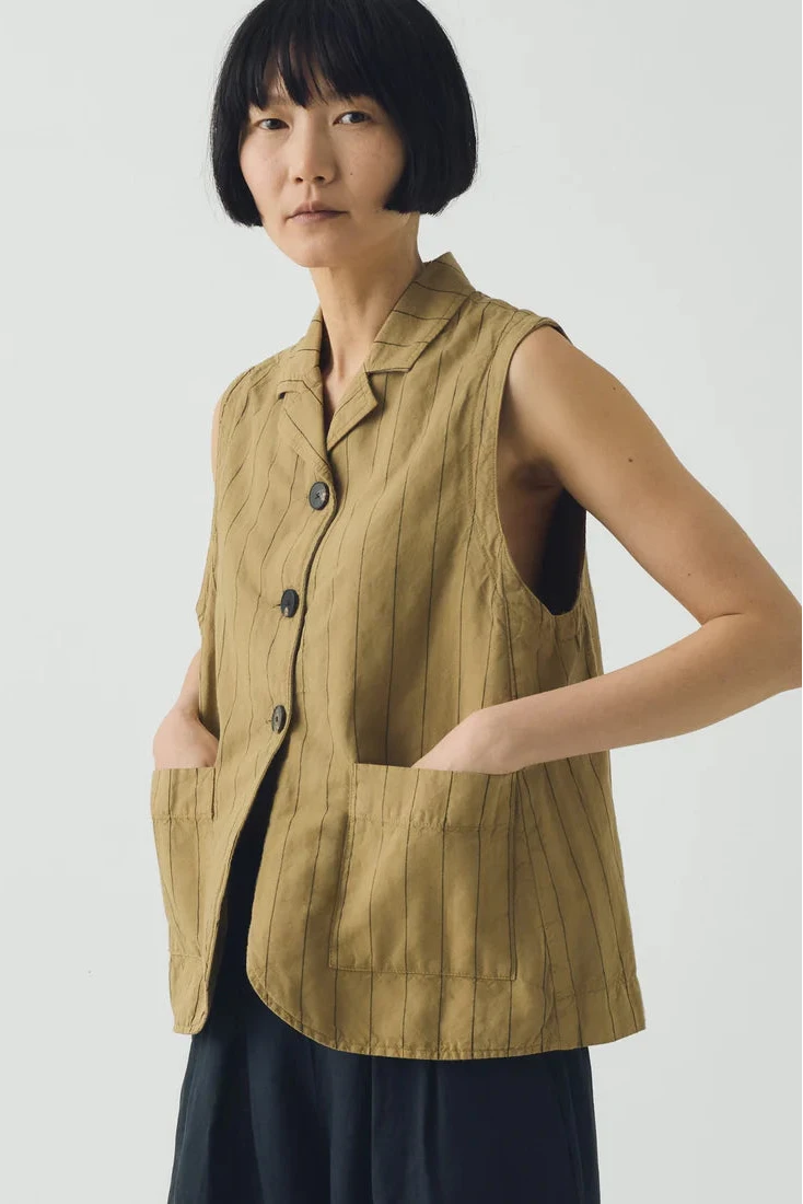 Woman wearing a mustard yellow waistcoat against a plain background
