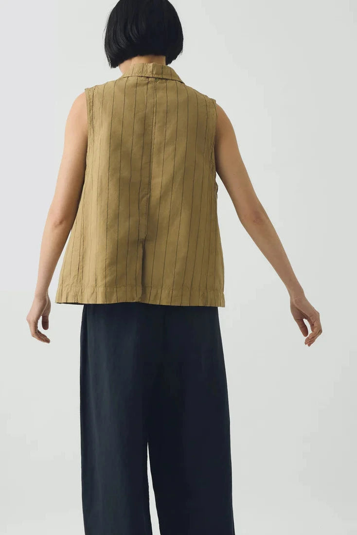 Person wearing a beige stripe waistcoat and dark pants on a white background