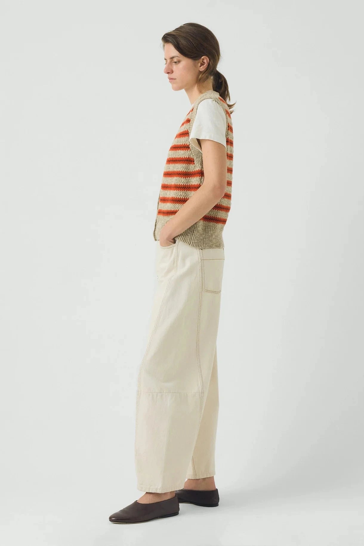 Woman wearing a striped shirt and beige pants on a white background
