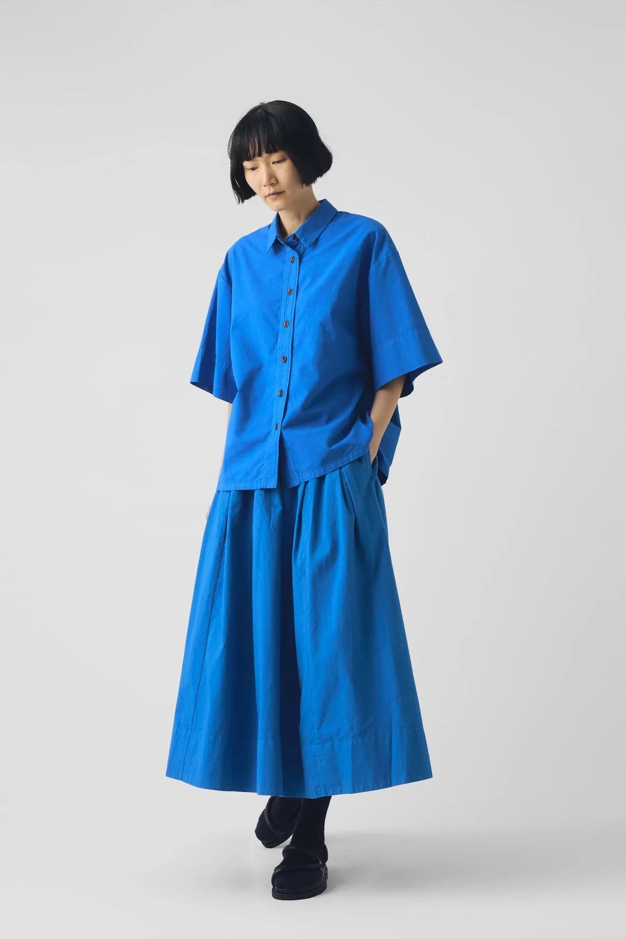 Person wearing a blue shirt and skirt on a white background