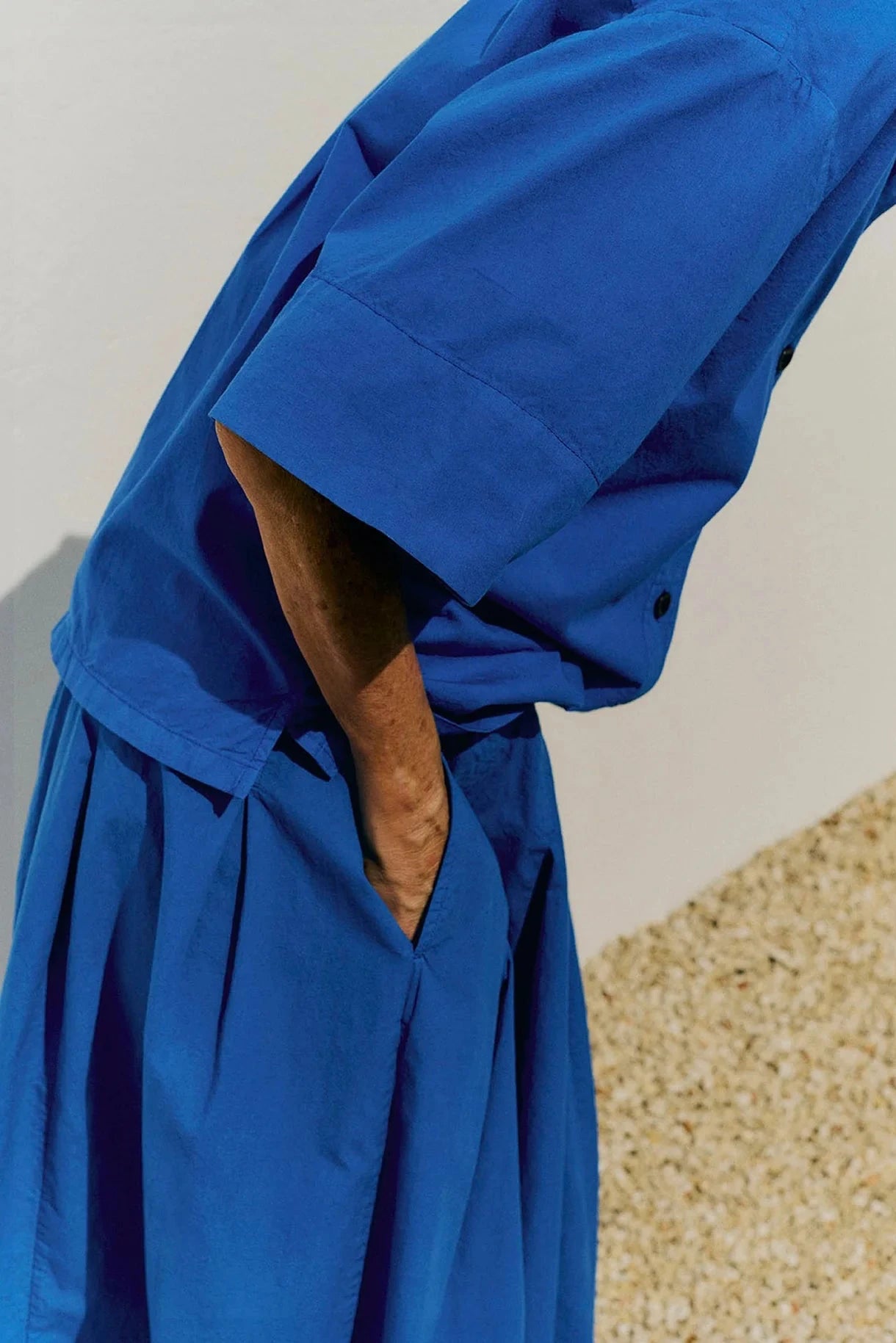 Person wearing a blue shirt and matching skirt with a neutral background