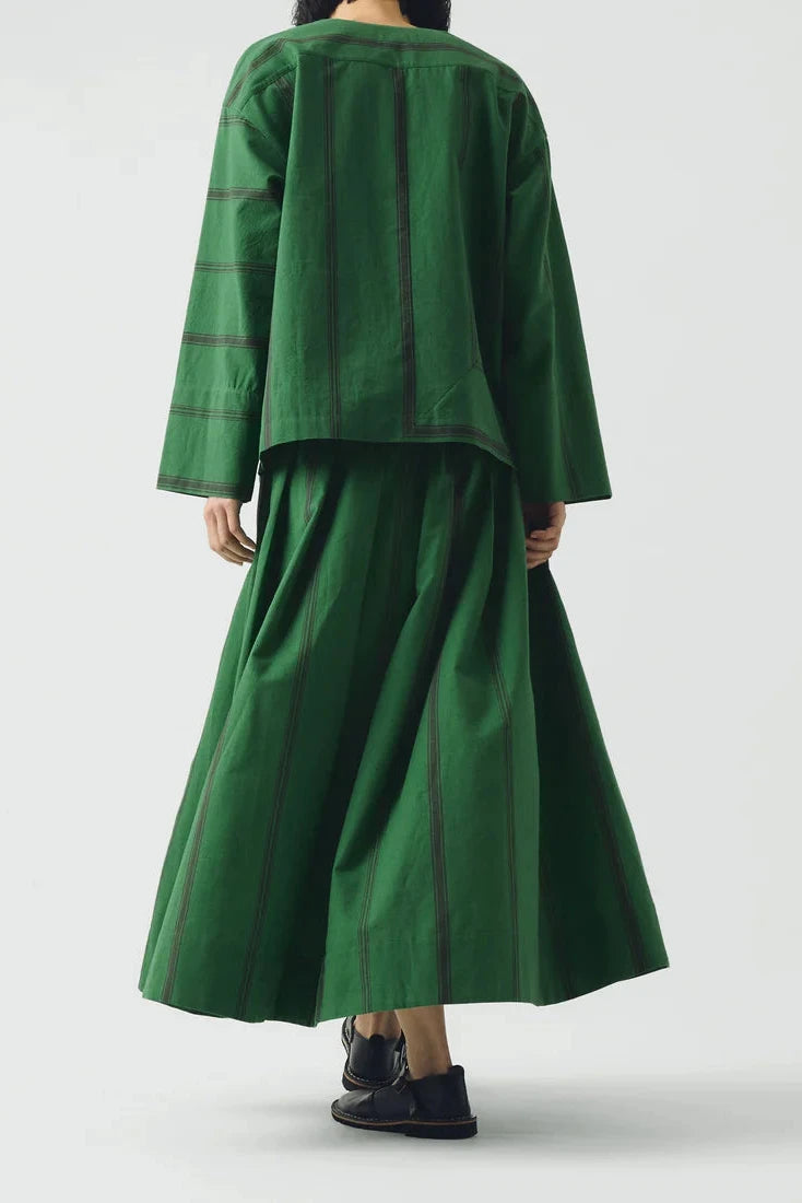 Person wearing a green outfit with a jacket and skirt on a white background