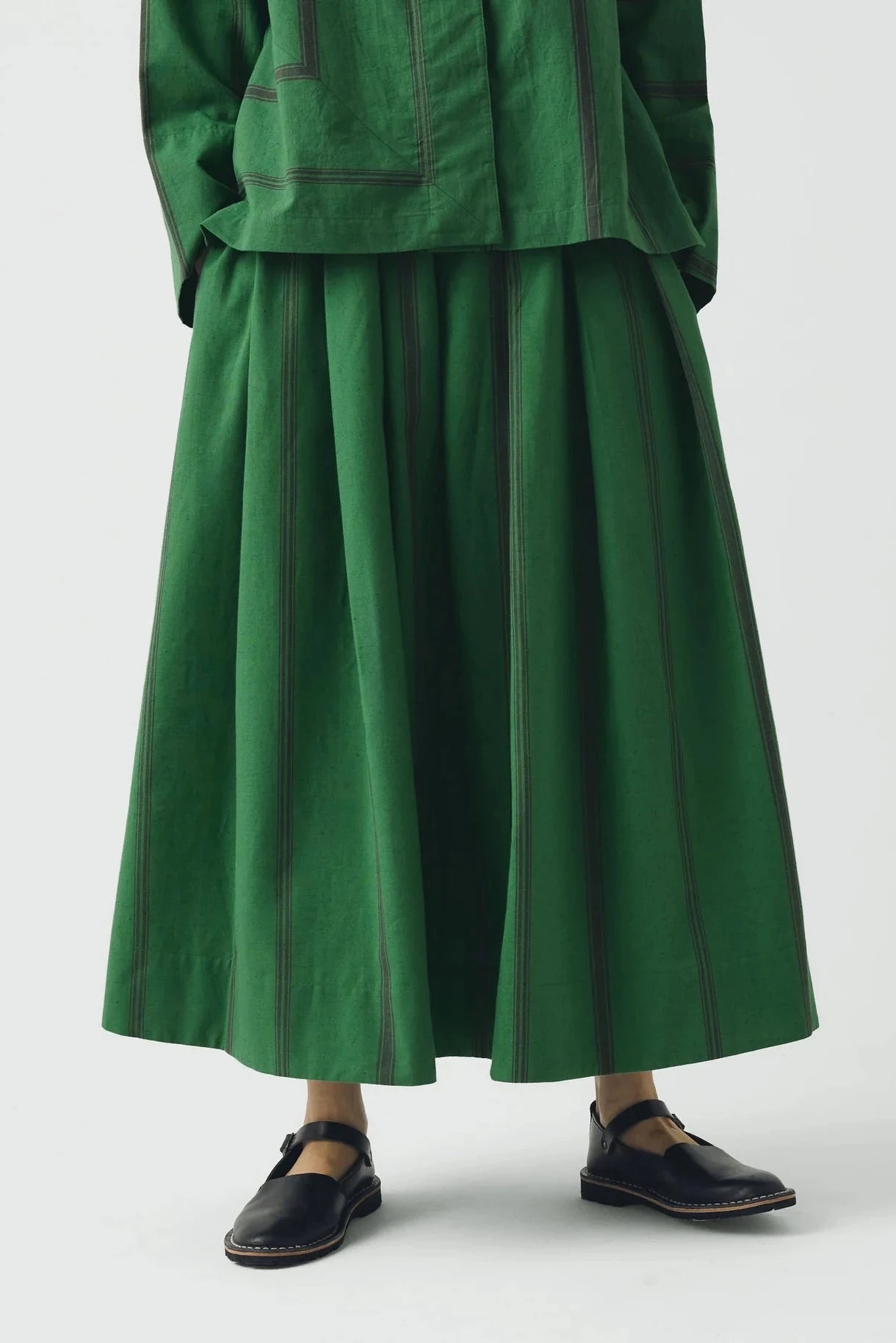 Green outfit with a long skirt and jacket on a white background