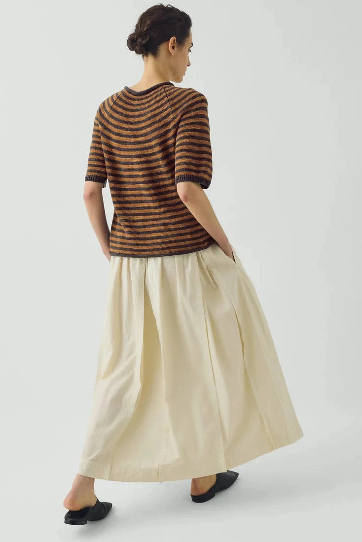 Rear view of the volumetric ecru TOAST skirt showing structured box pleats and midi length