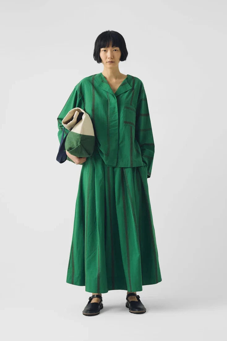 Person wearing a green outfit holding a bag on a white background