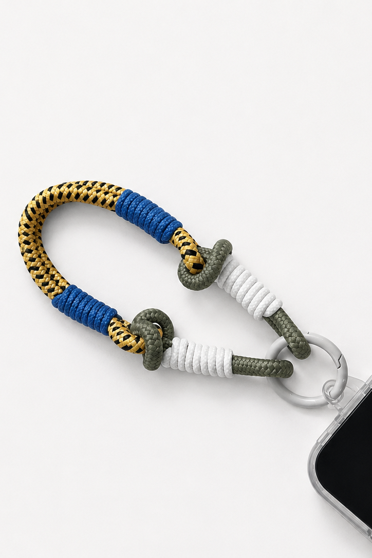 A paracord phone strap with blue, gold, and white wrapped sections, attached to a silver metal ring and shown holding a smartphone on a white background - East Coast General