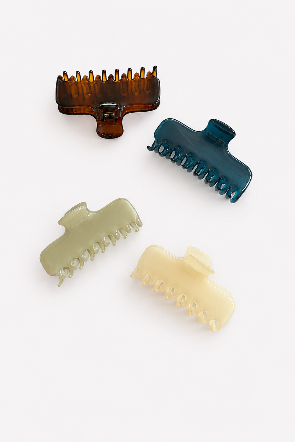 Four hair claw clips in assorted translucent colors, including amber brown, teal blue, sage green, and cream yellow, arranged on a light gray background - East Coast General