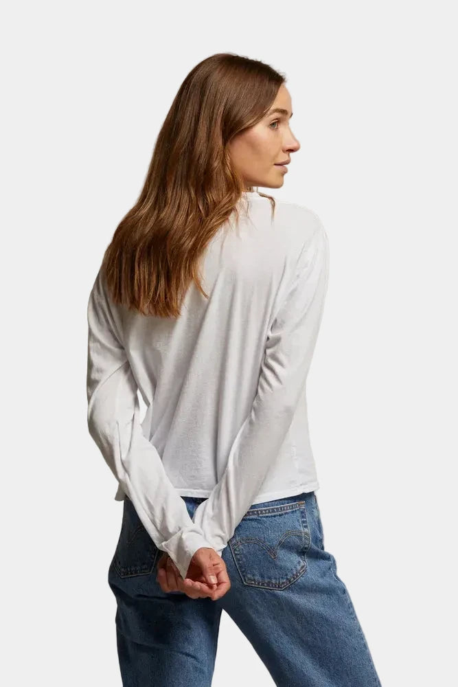 Woman wearing a white shirt and blue jeans against a beige background