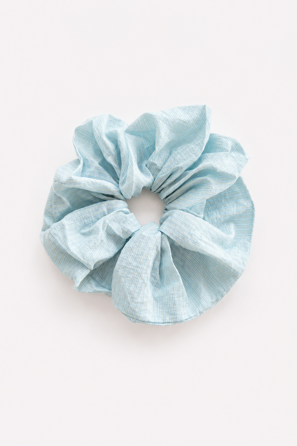 A single light blue stripe scrunchie made from textured, crinkled fabric, photographed flat against a clean off-white background - East Coast General