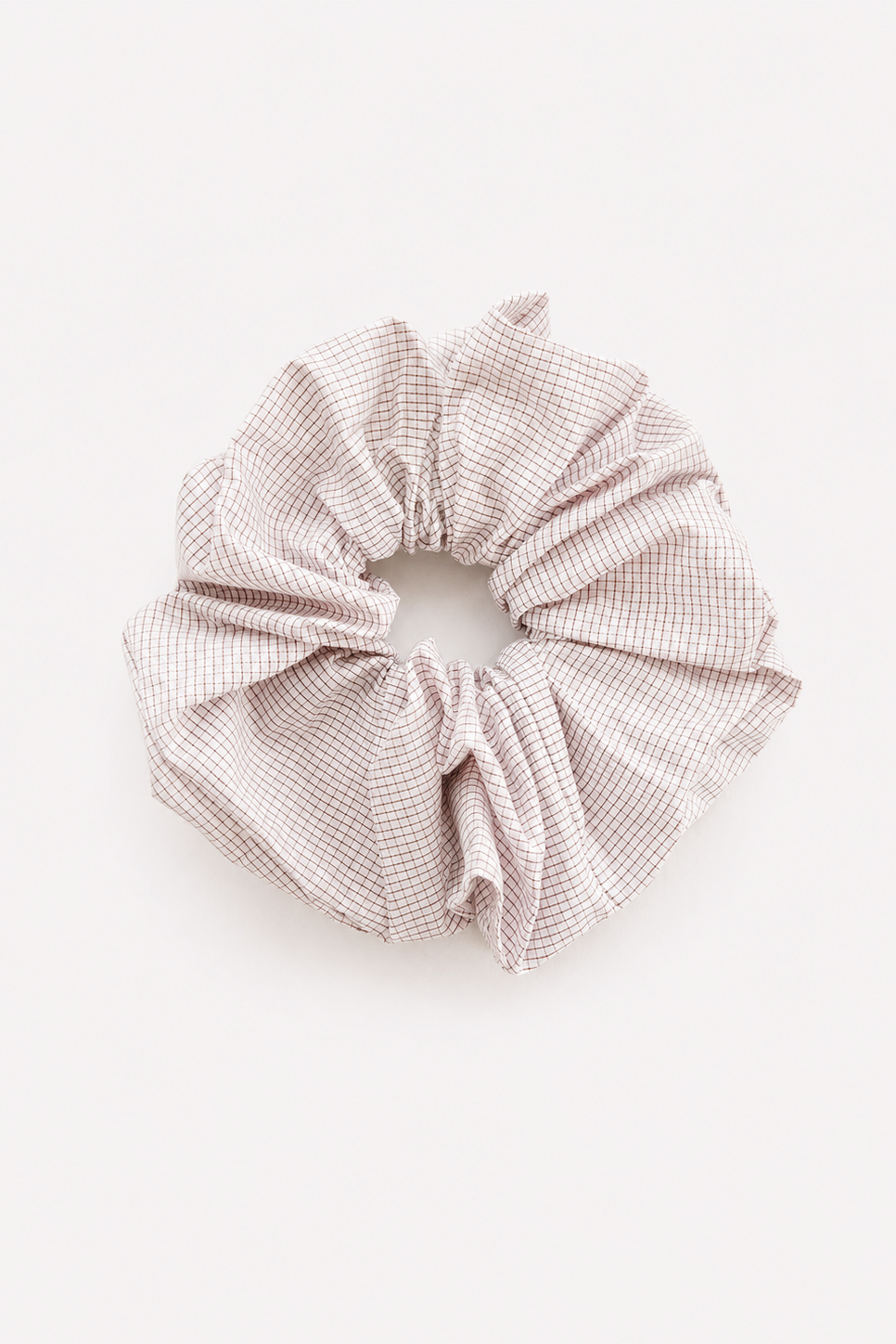 A fabric hair scrunchie with a small brown and white gingham checkered pattern, photographed flat on a light off-white background - East Coast General