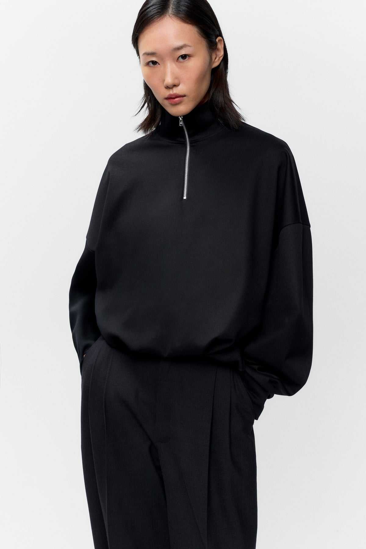 Front view of model wearing Cordera black balloon quarter zip pullover with silver hardware - East Coast General