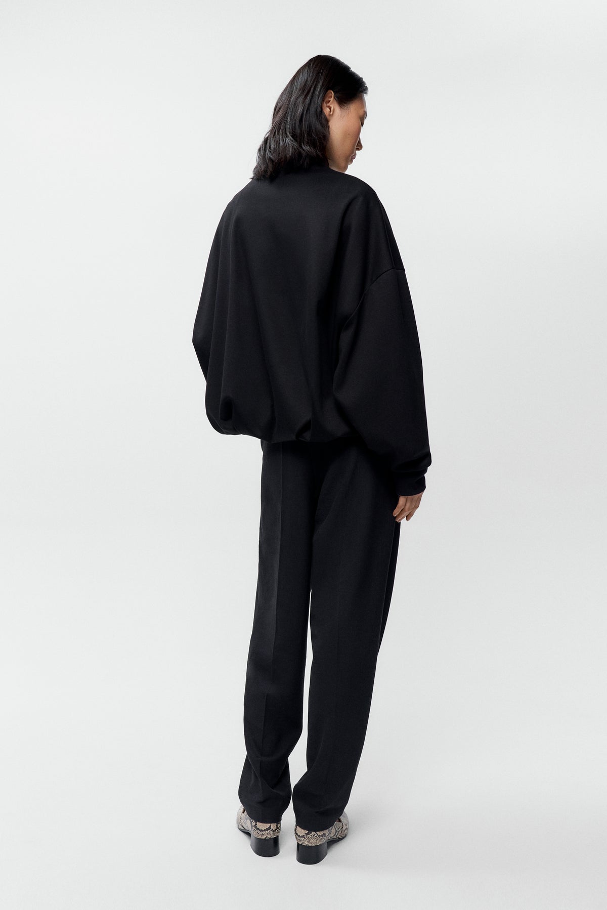 Rear view of model wearing Cordera black balloon quarter zip pullover - Est Coast General
