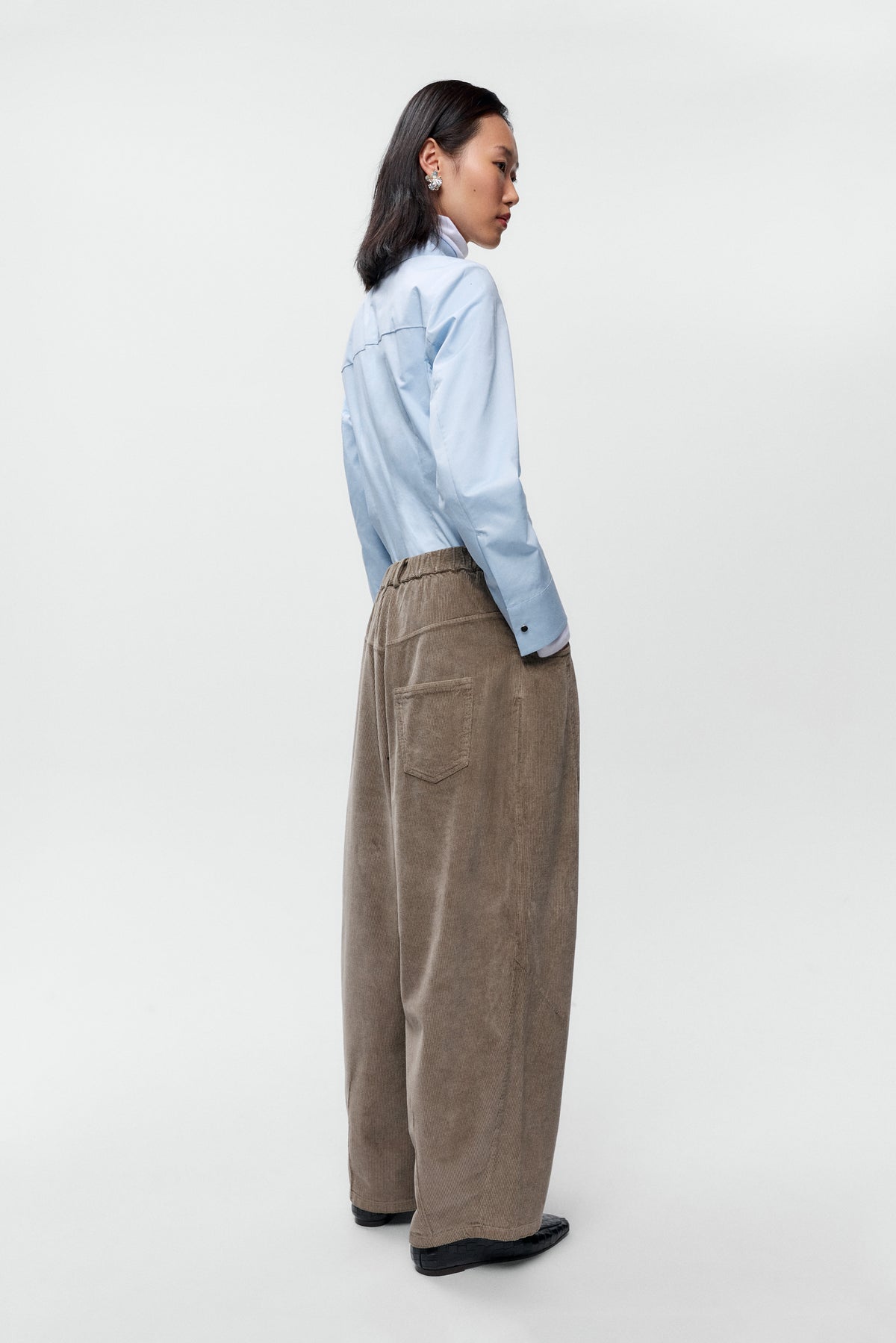 Side back view of model wearing Cordera corduroy baggy pants in sage with wide leg fit - East Coast General