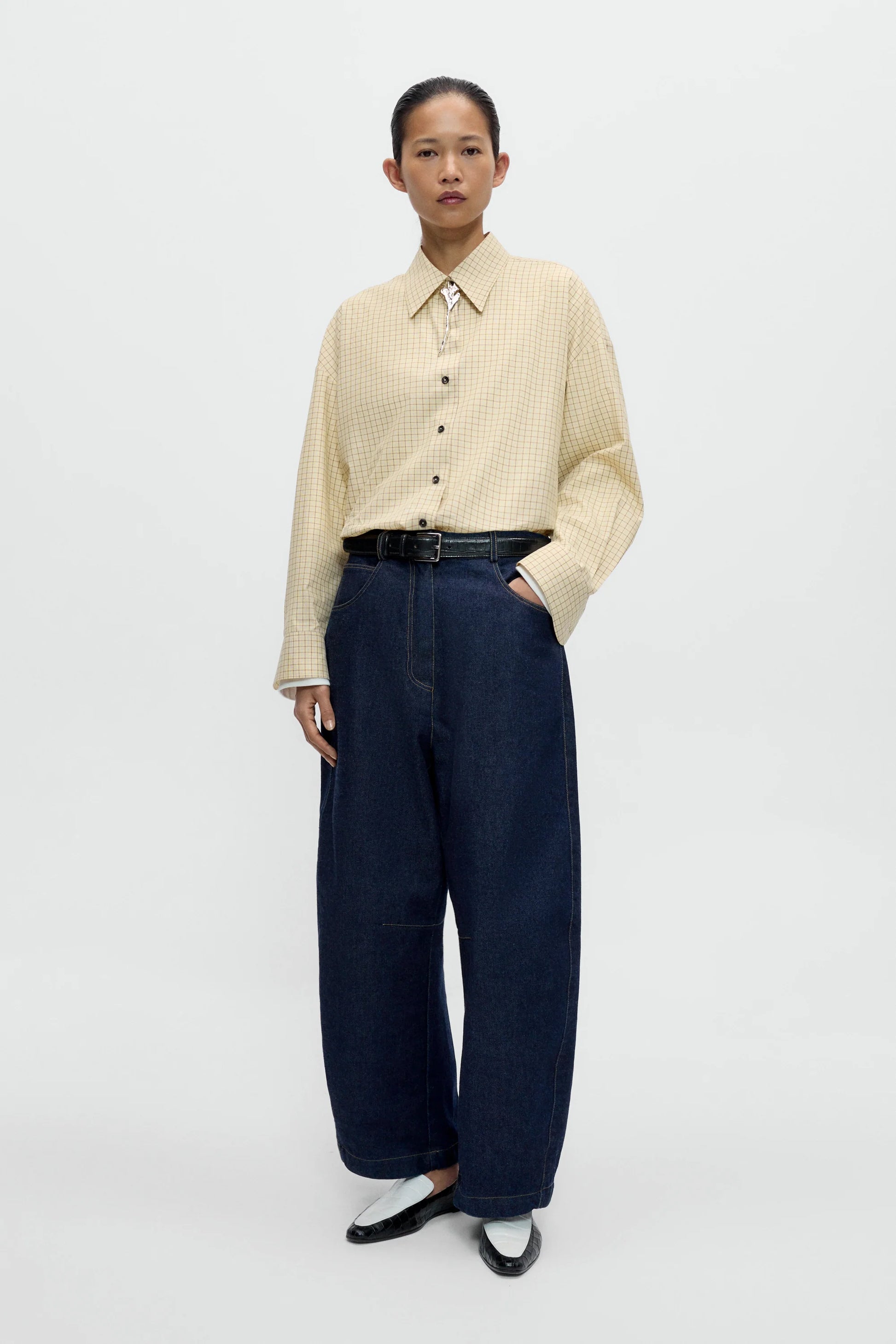 A lady wearing a yellow checked shirt with wide dar indigo jeans