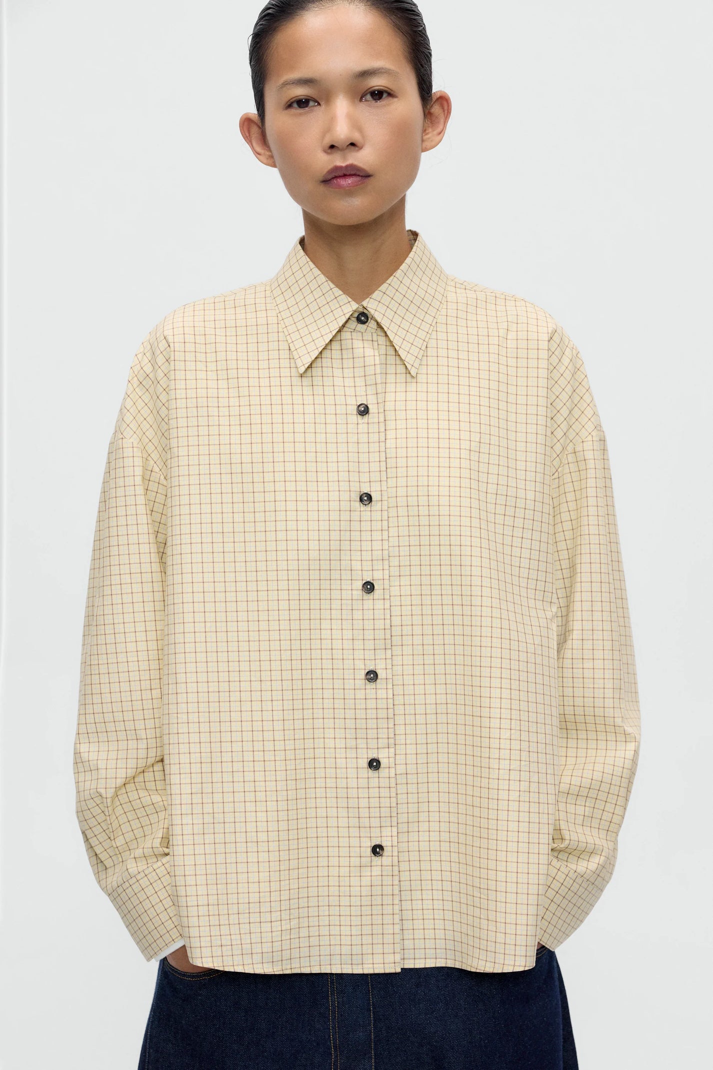 Person wearing a beige checkered shirt on a white background
