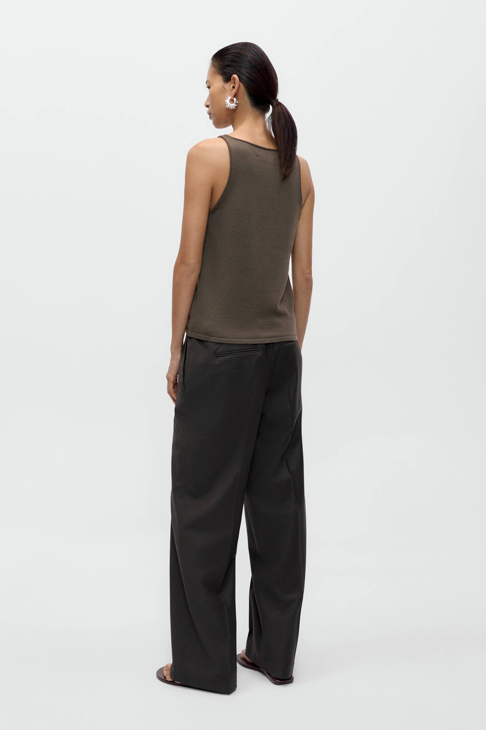 Woman wearing a brown tank top and black pants on a white background