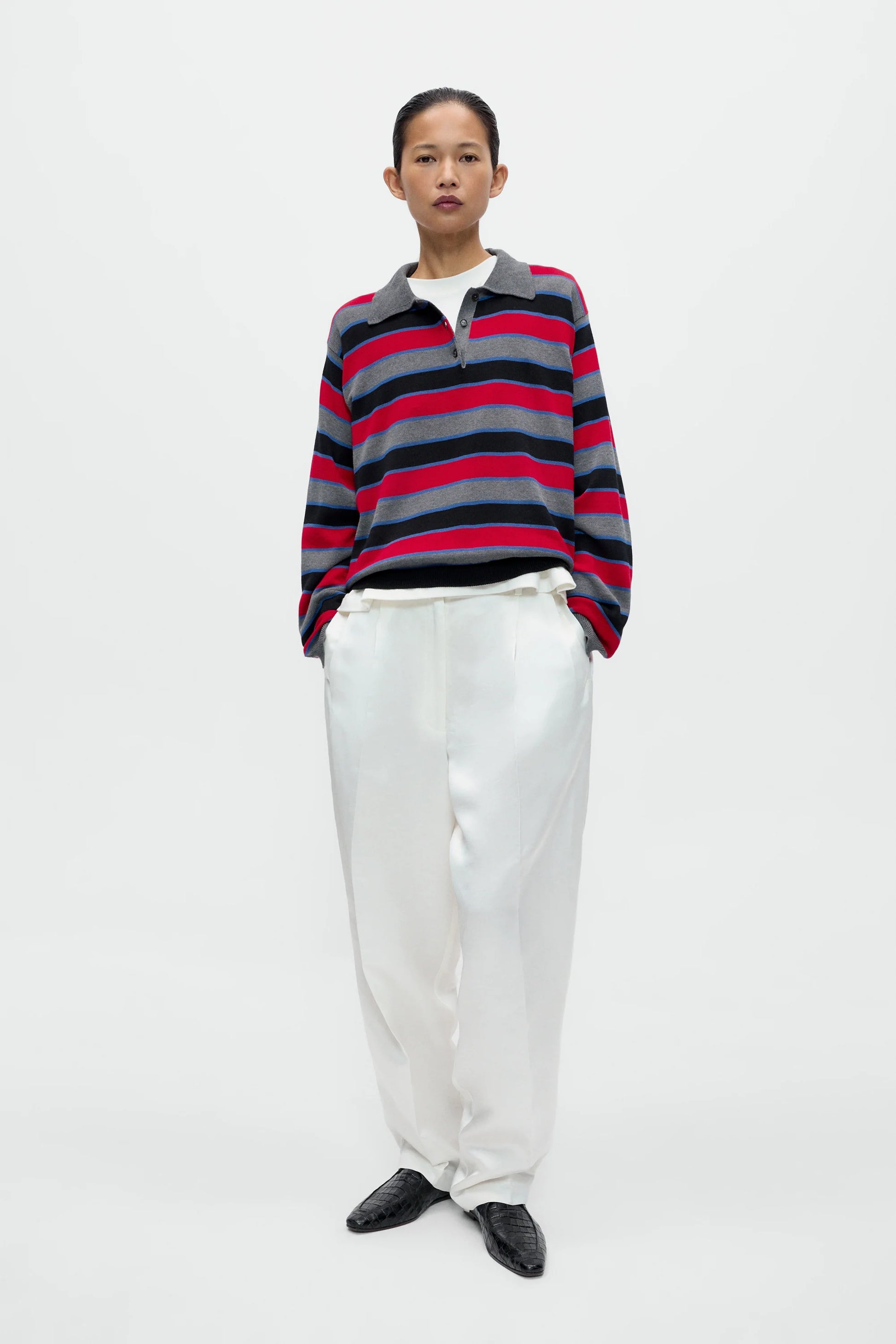 Person wearing a striped sweater and white pants on a white background