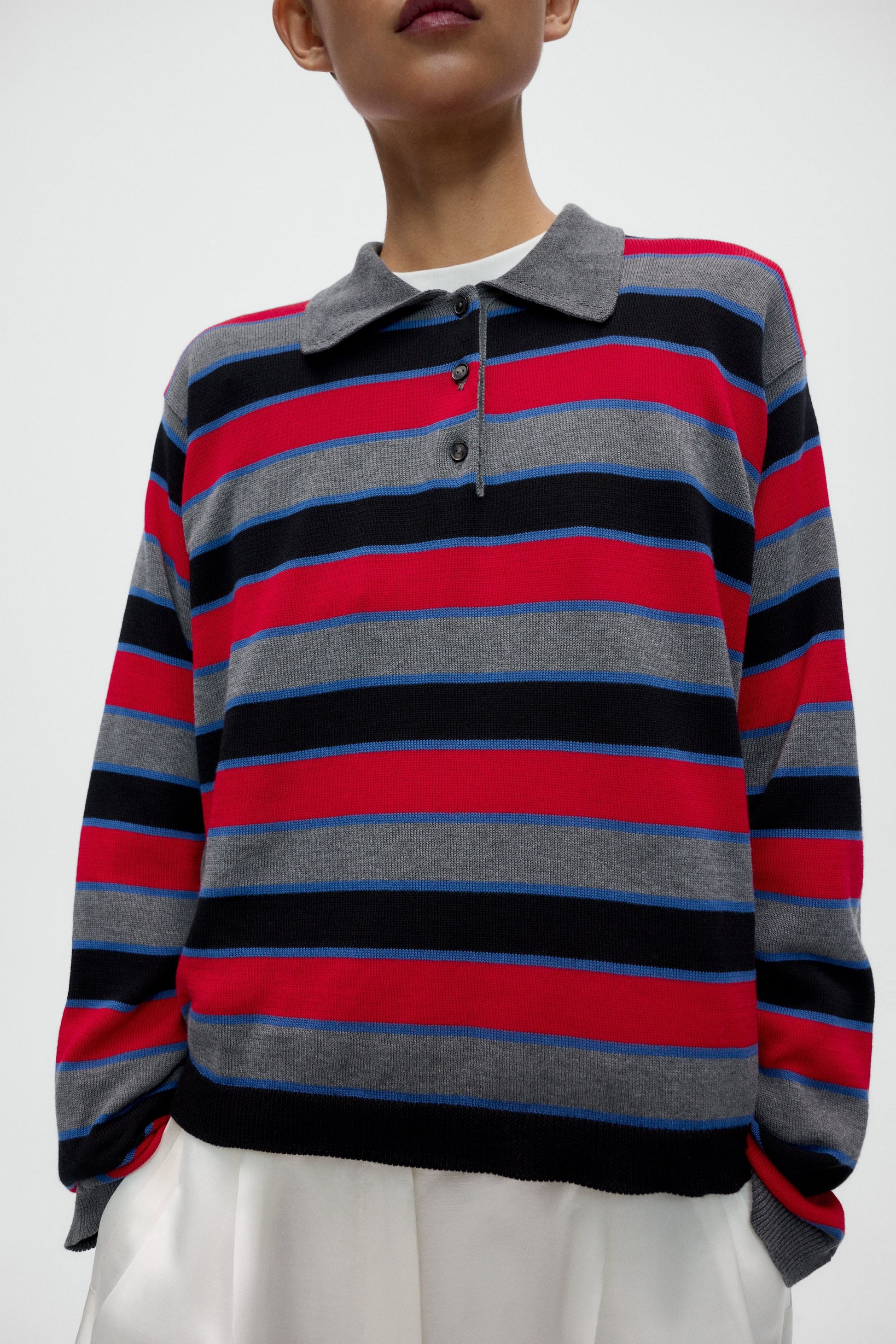 Person wearing a multicolored striped sweater with a white background