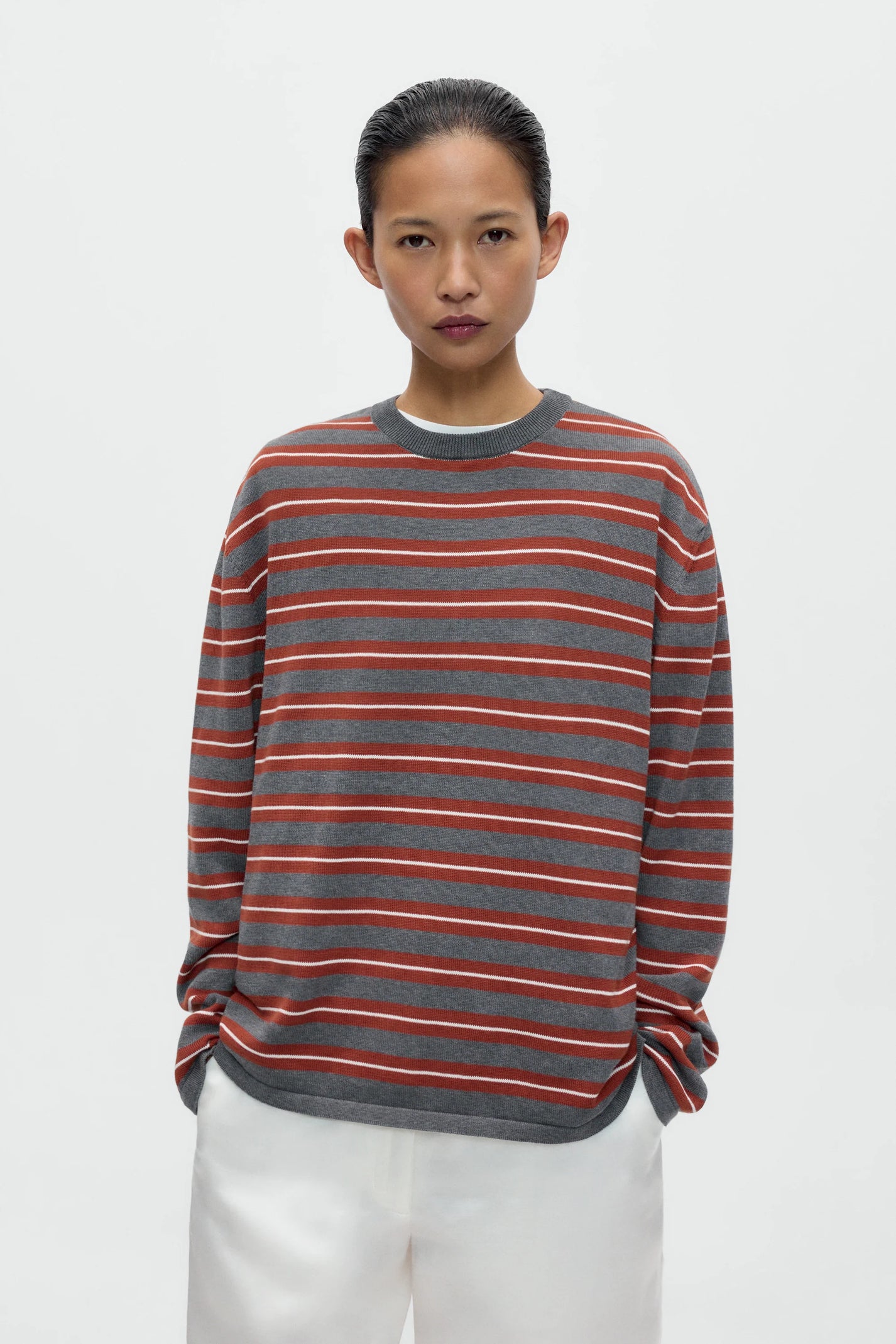 Person wearing a striped sweater with red and gray horizontal lines on a white background