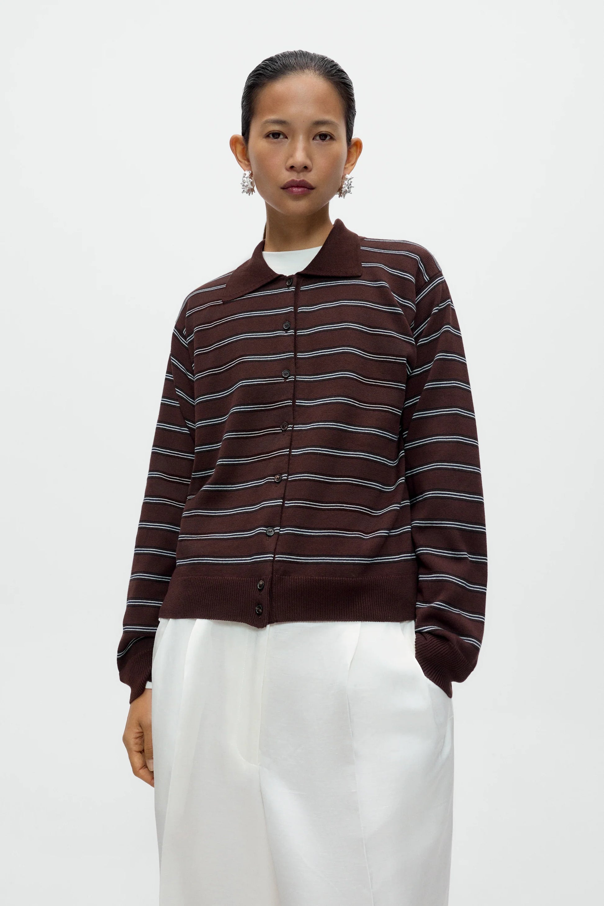 Person wearing a brown and white striped shirt with a plain background