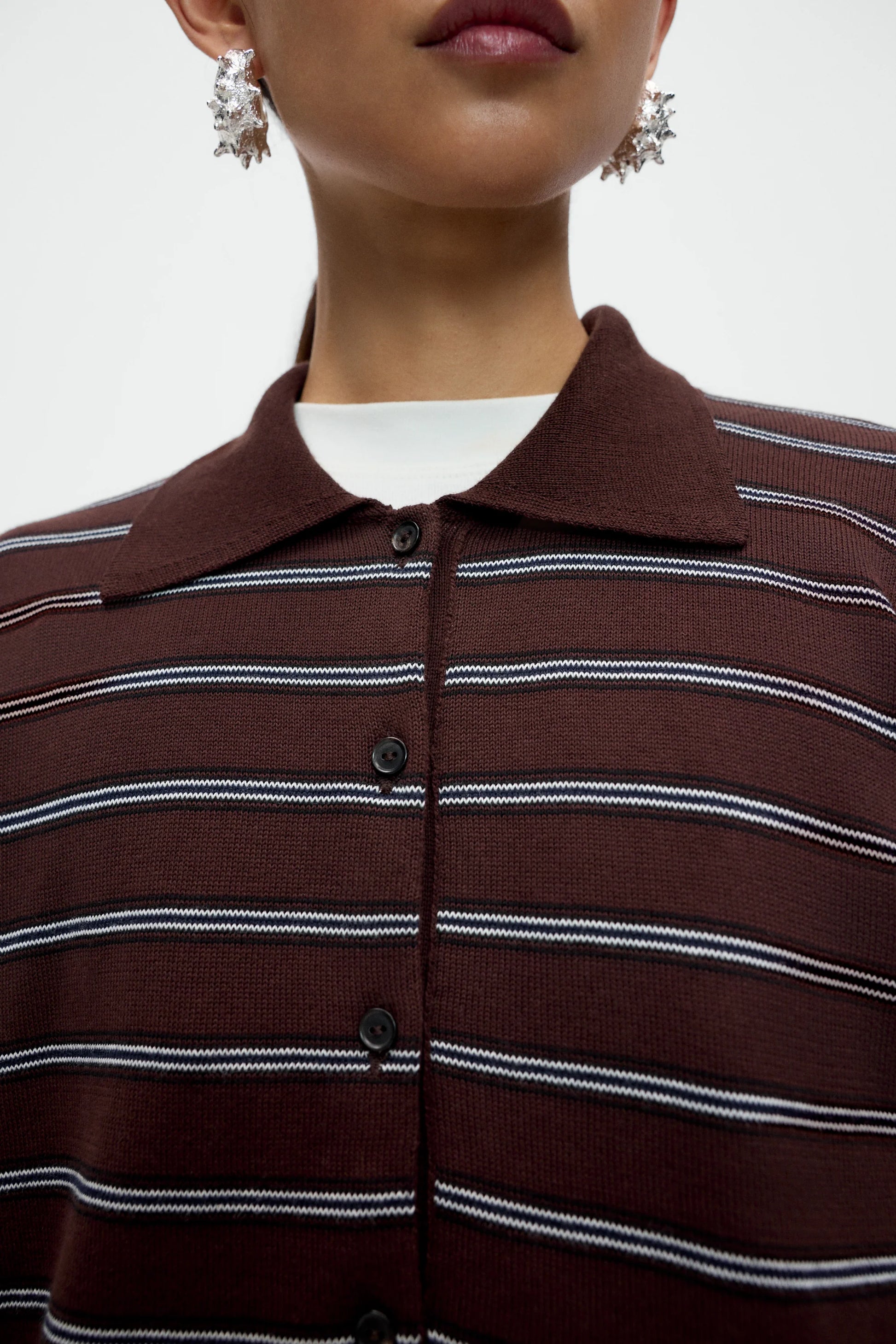 Close-up of a person wearing a brown and white striped shirt with a blurred background