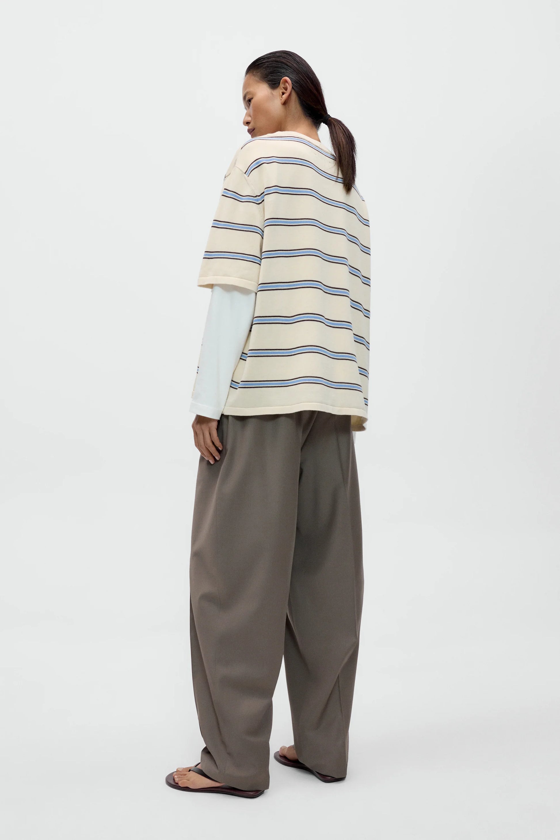 Person wearing a striped sweater and wide-leg pants on a white background