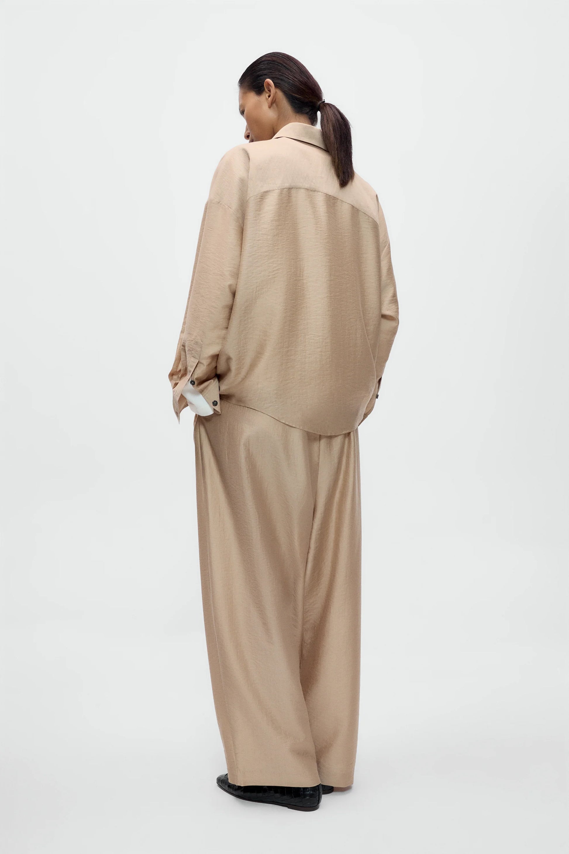 Person wearing a beige outfit on a white background