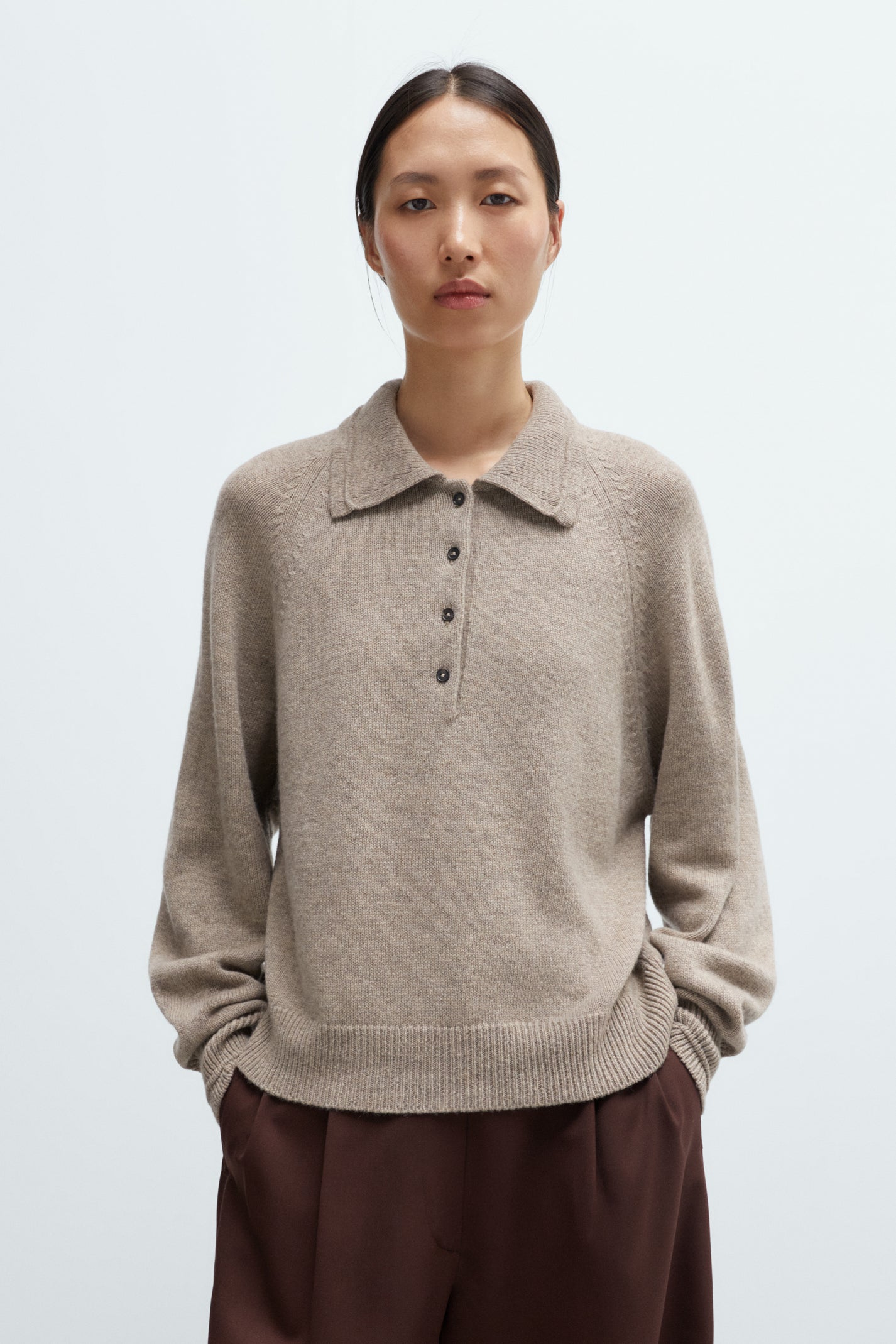 Person wearing a beige sweater with a collar against a light background