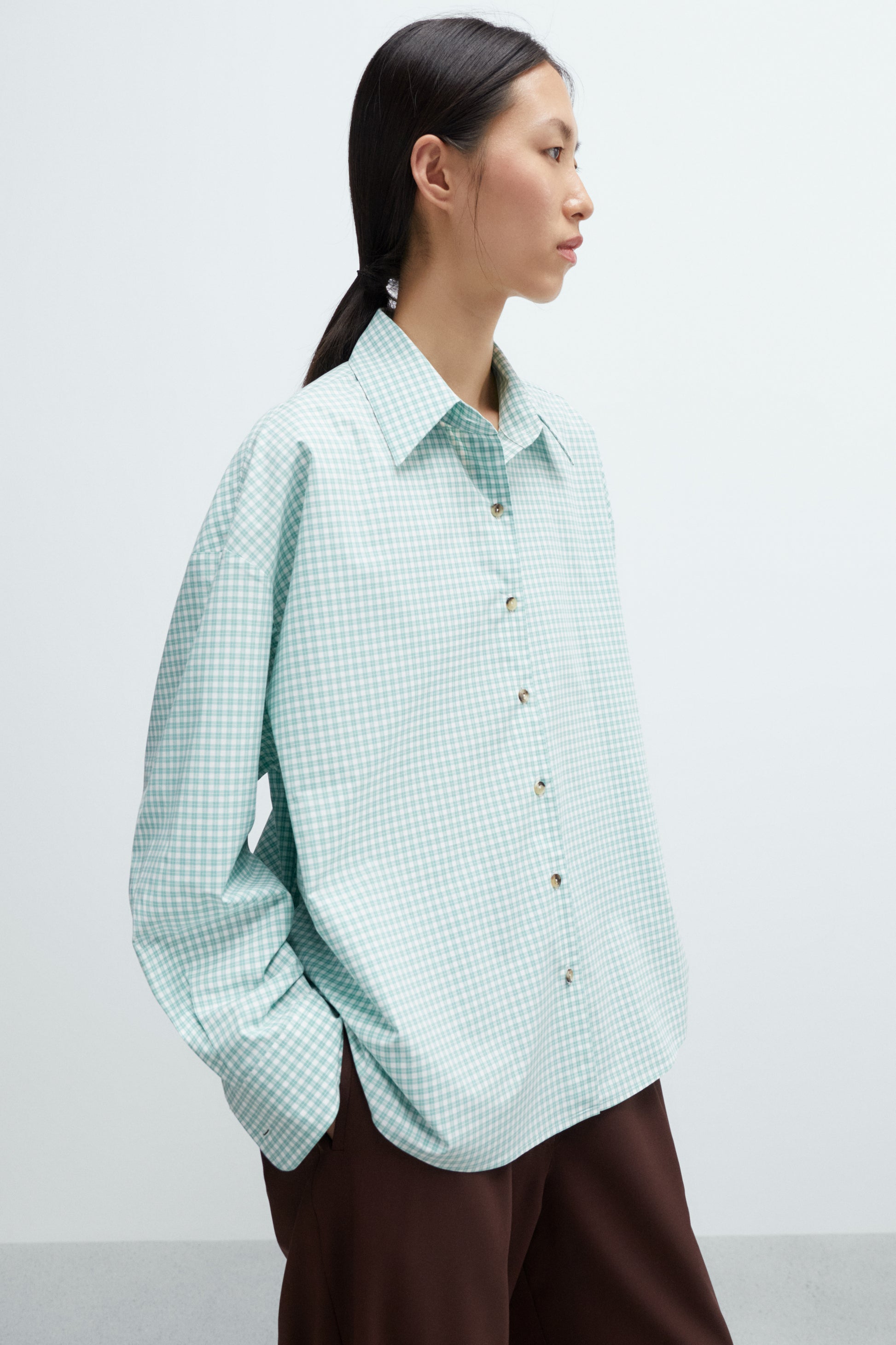 Person wearing a light green checkered shirt against a white background