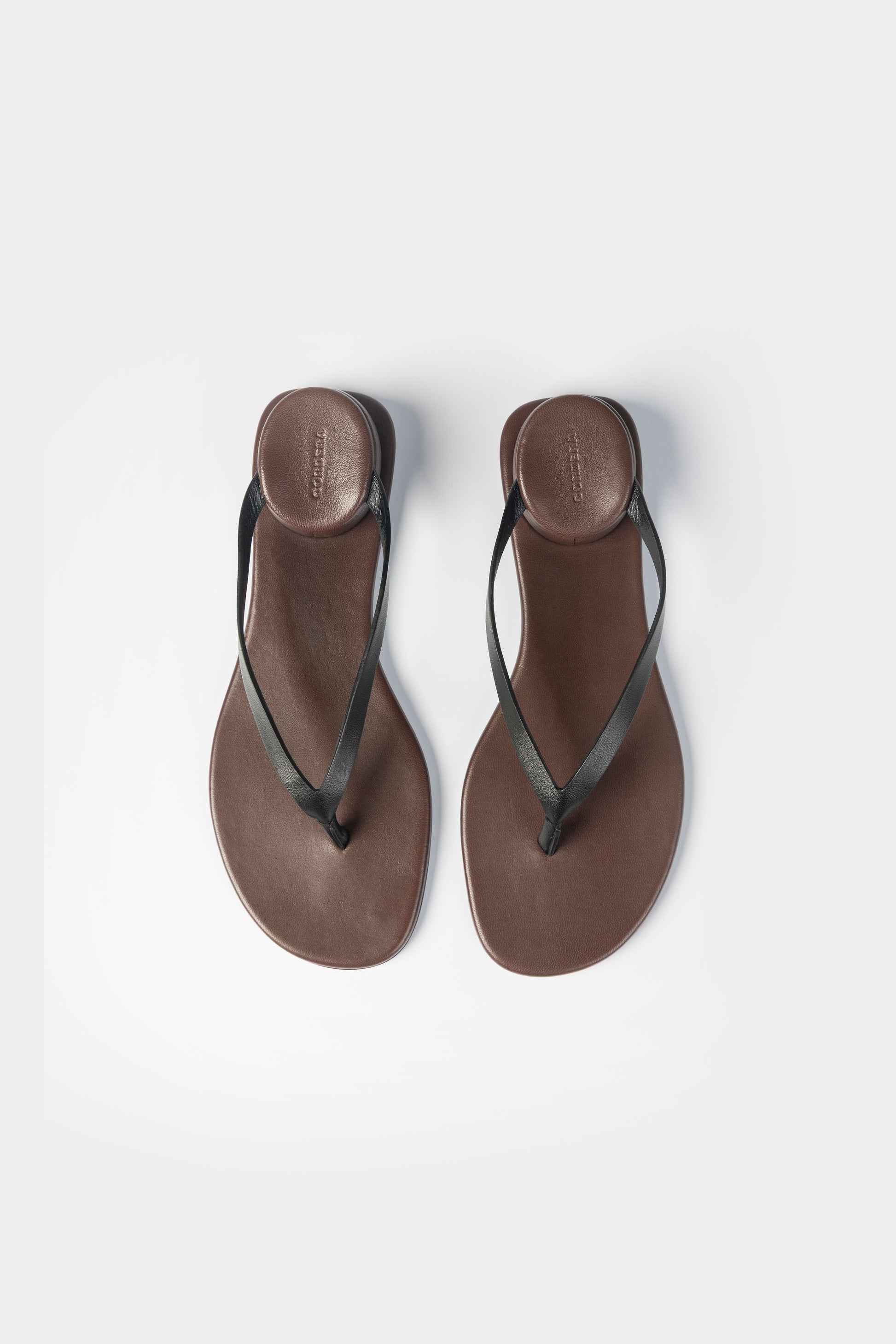 Pair of brown sandals with black straps on a white background