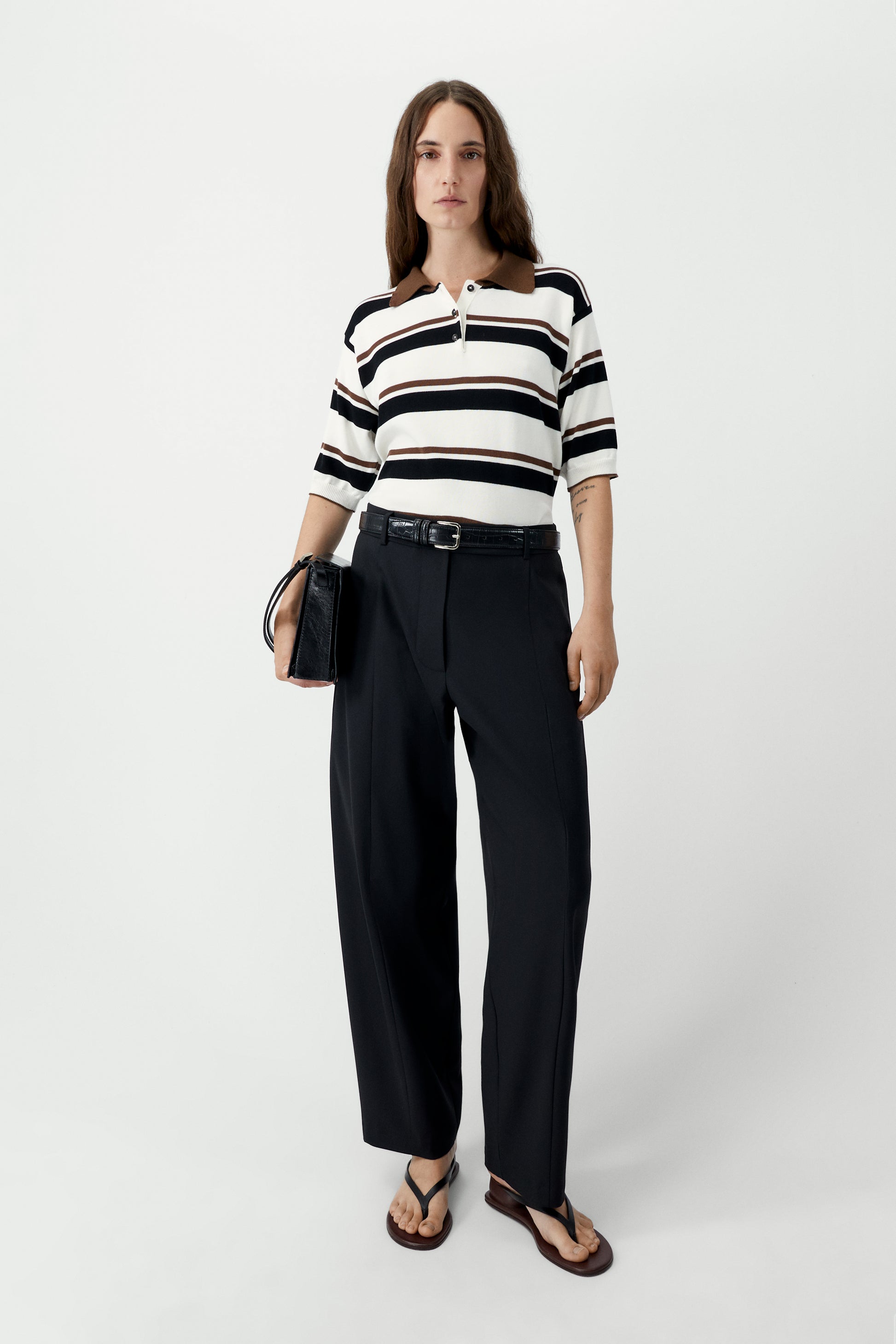 Woman wearing a black and white striped shirt with black pants on a white background