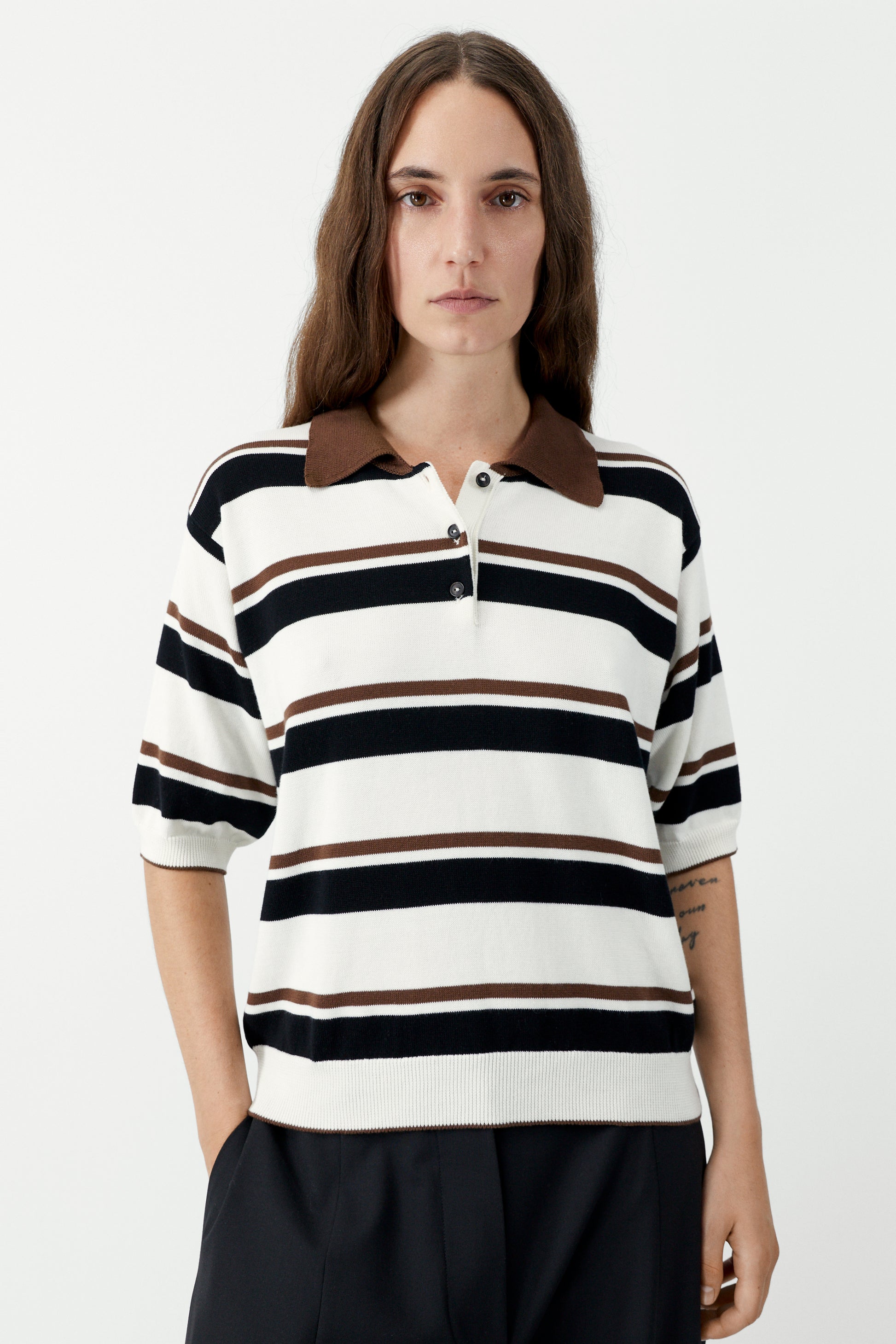 Woman wearing a striped polo shirt with a brown collar on a white background