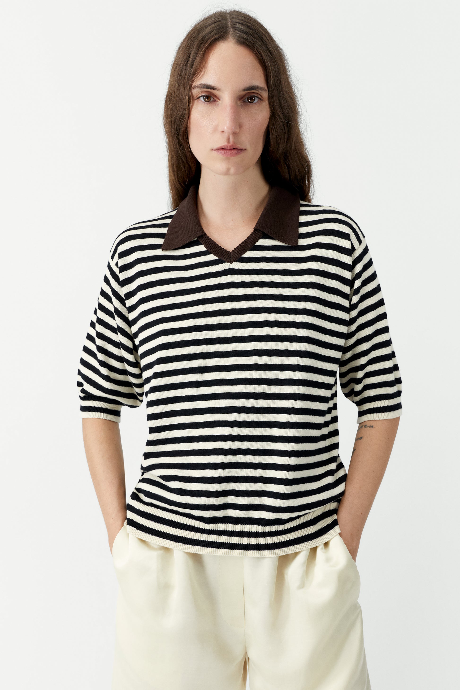 Woman wearing a black and white striped shirt with a brown collar on a white background