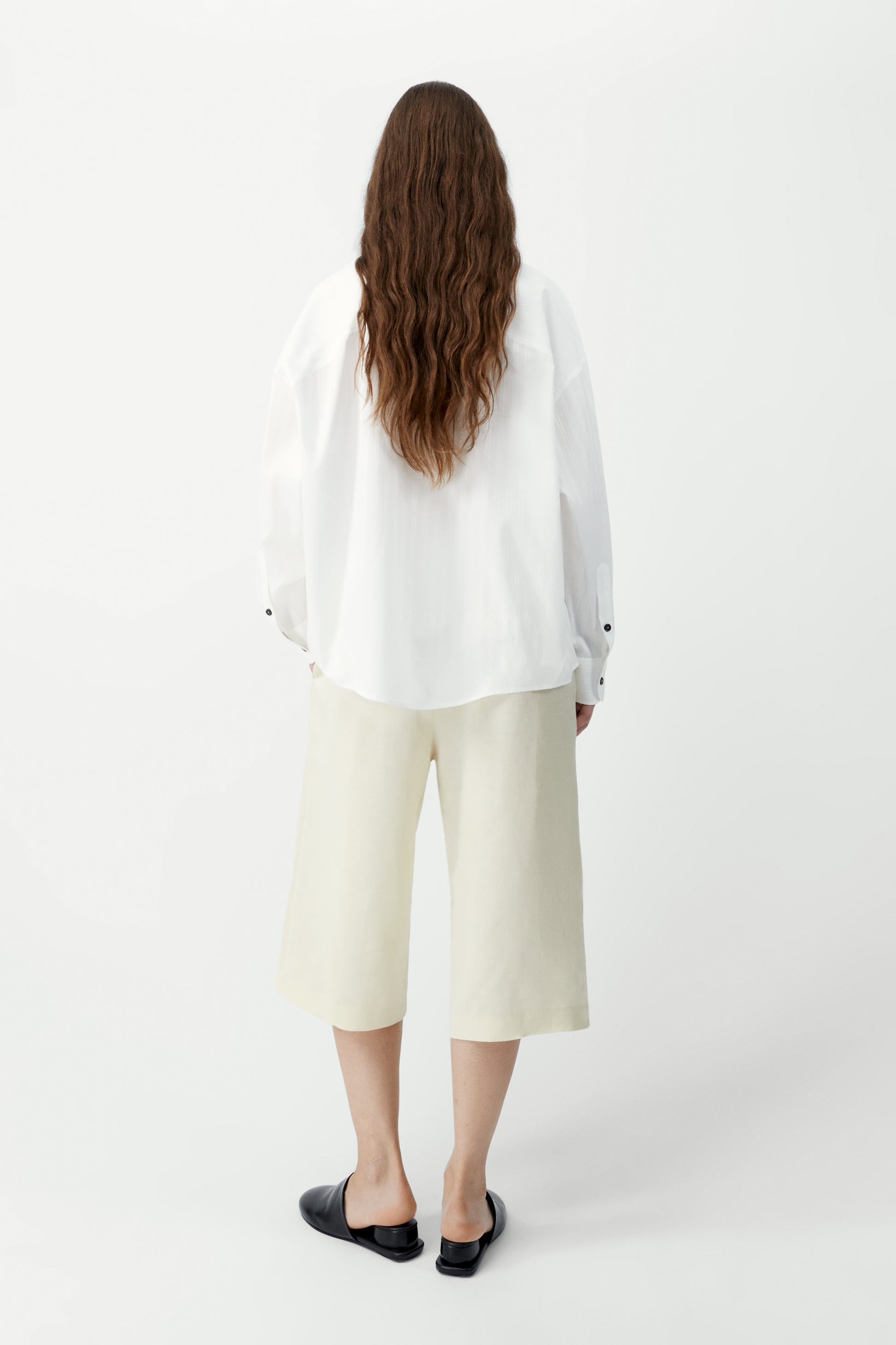 Person wearing a white jacket and cream-colored pants on a white background