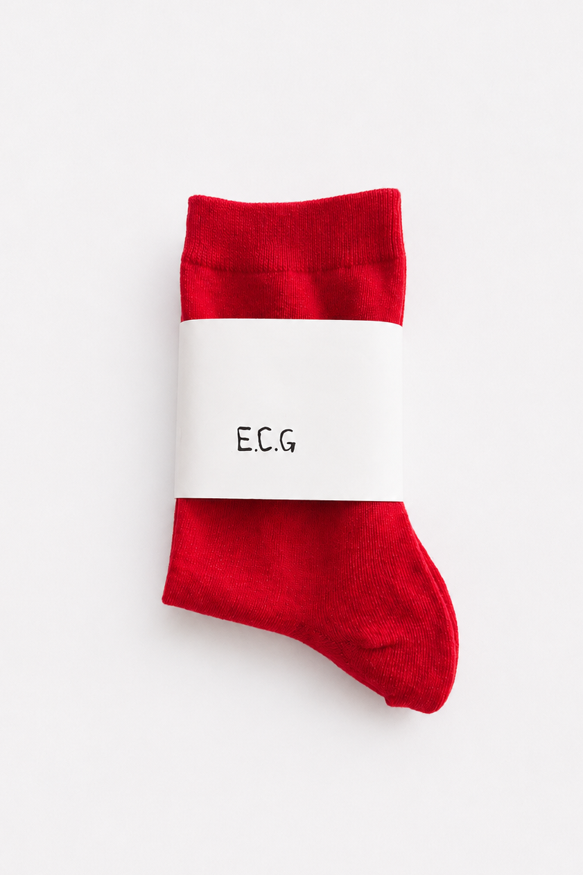 A pair of cotton red crew socks with a white paper band around the middle printed with the brand name 'E.C.G - East Coast General