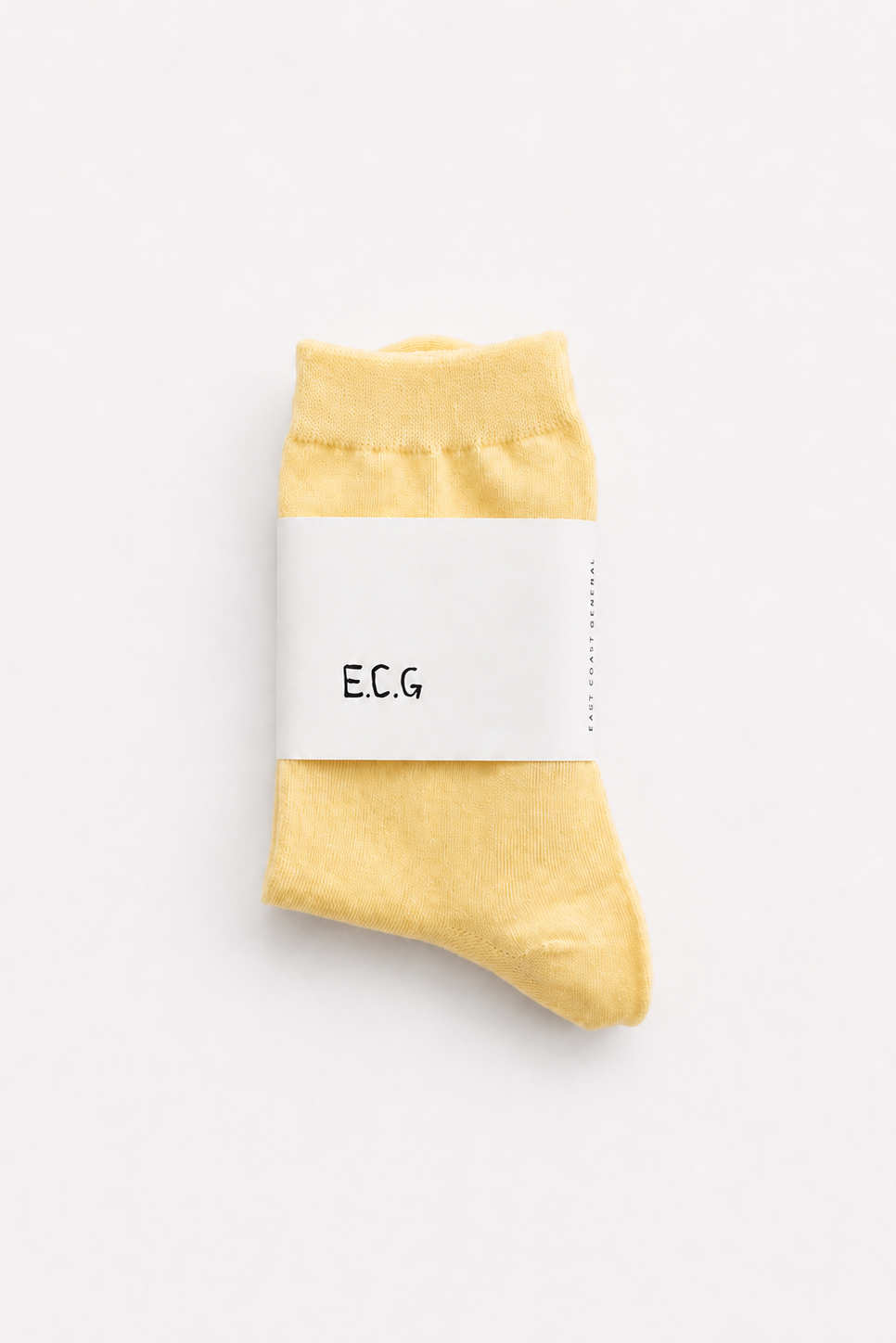 A single pale yellow sock wrapped in a white paper band printed with the brand name 'E.C.G - East Coast General