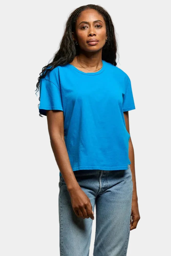 Woman wearing a blue t-shirt and jeans against a plain background