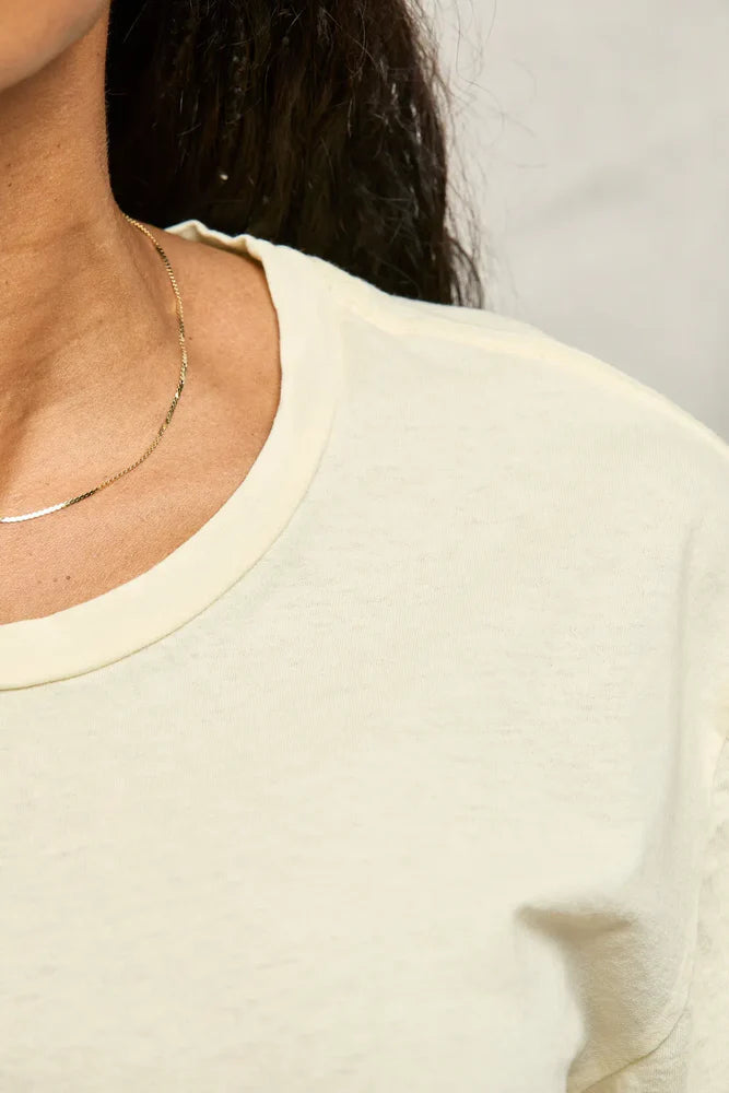 Close-up of a person wearing a light-colored top with a blurred background