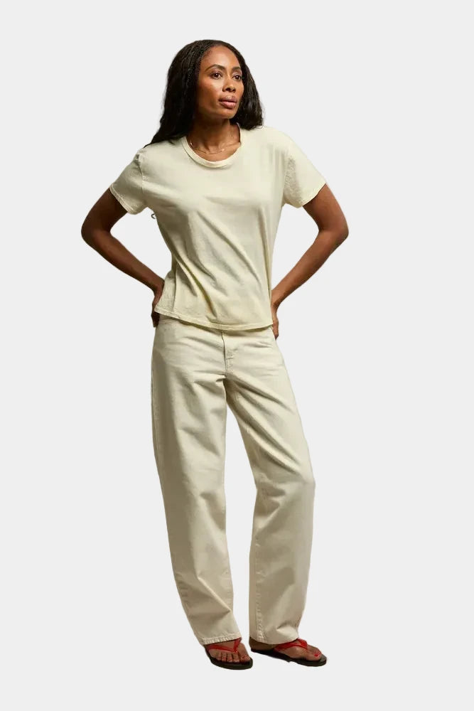 Woman wearing a white t-shirt and pants against a plain background