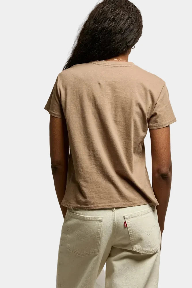Person wearing a beige t-shirt and light-colored pants against a plain background
