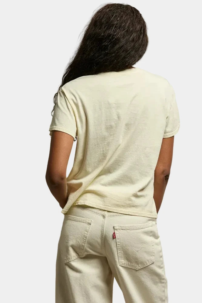 Person wearing a light-colored t-shirt and pants against a neutral background